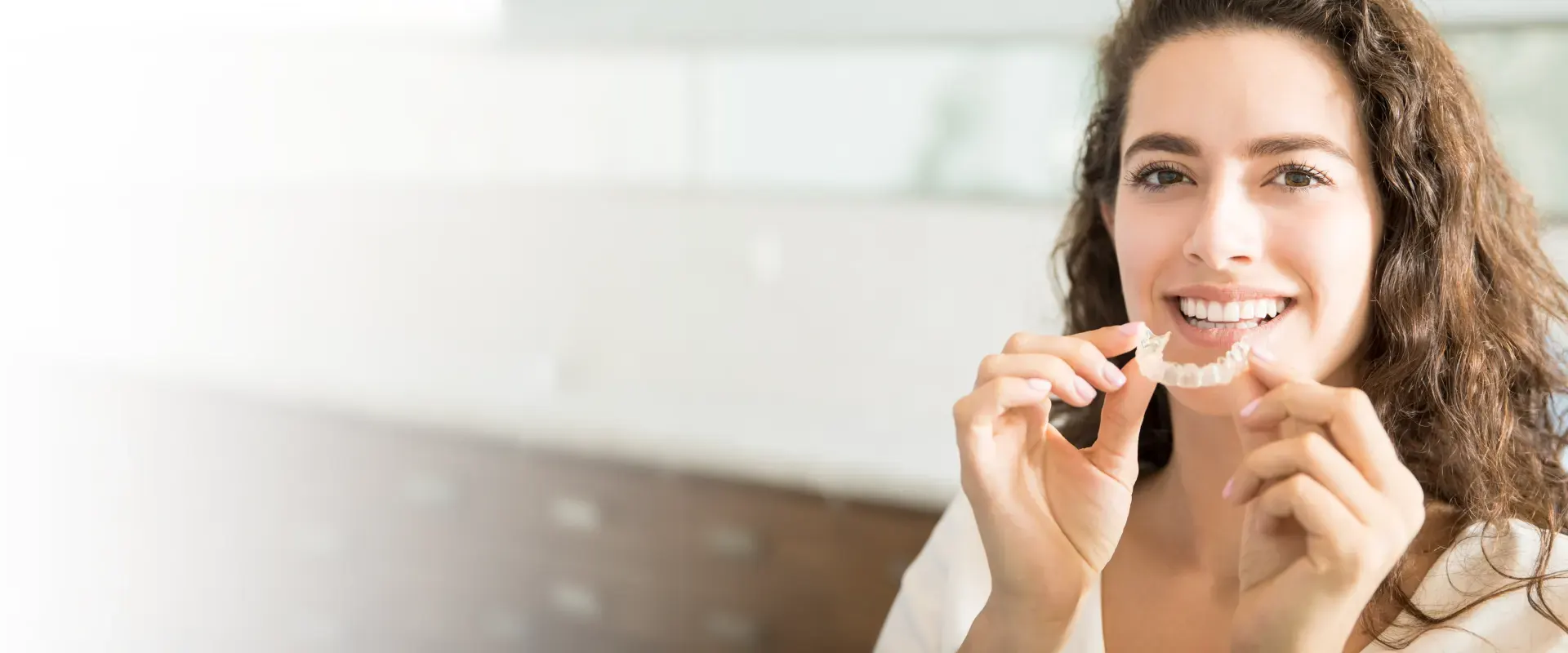 A woman holding a clear Invisalign aligner