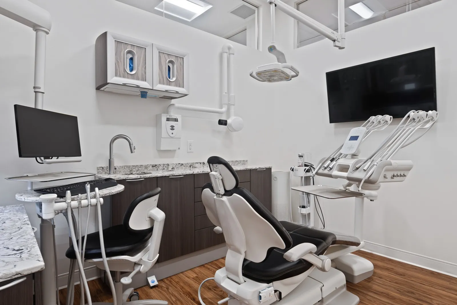 A Terry Fox treatment room with a cream dental chair and ceiling-mounted monitor